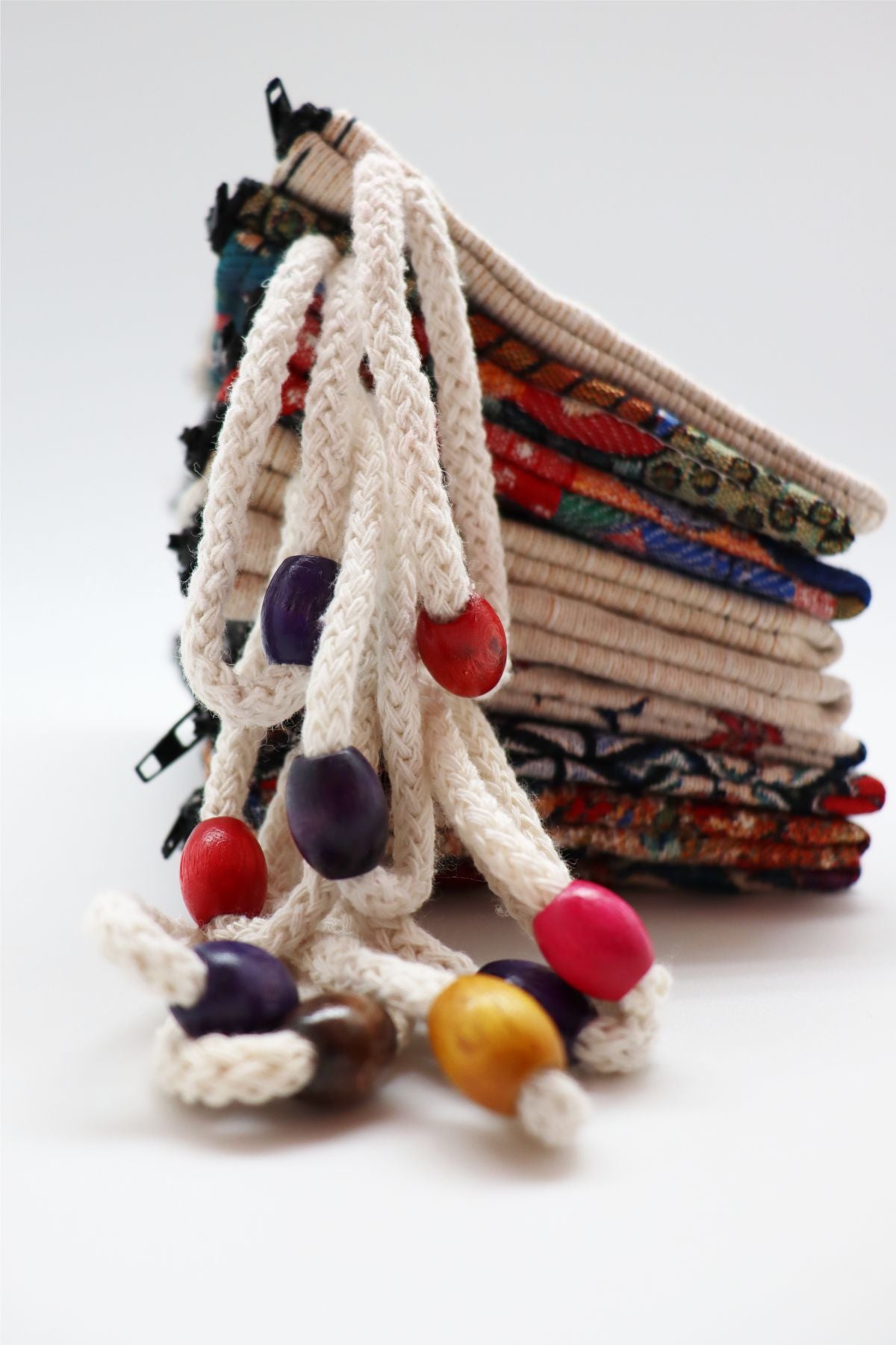 Woven wallets stacked, showing the wrist straps and wooden beads